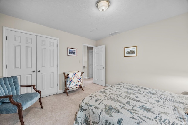 bedroom with light carpet, a closet, and a textured ceiling