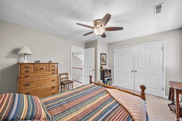 carpeted bedroom with a textured ceiling, a closet, and ceiling fan