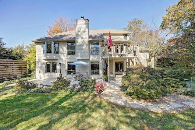 rear view of property with a deck, a lawn, and a patio