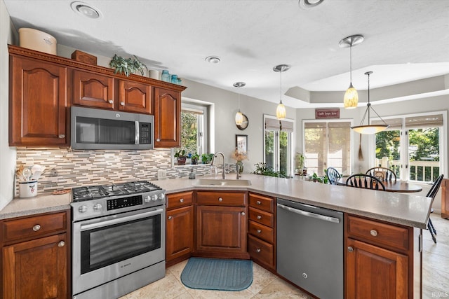 kitchen with backsplash, pendant lighting, sink, a healthy amount of sunlight, and stainless steel appliances