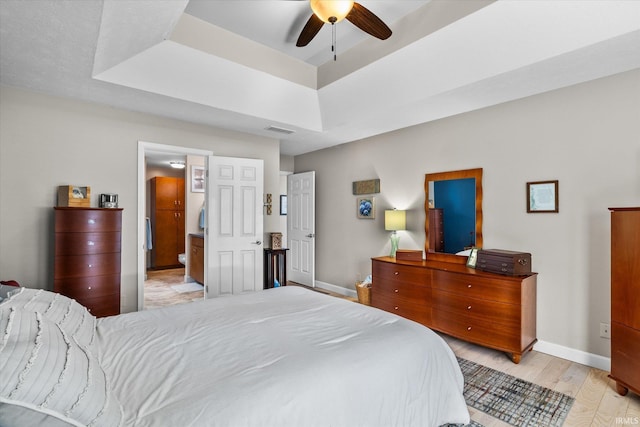 bedroom featuring light wood-type flooring, ceiling fan, and a tray ceiling