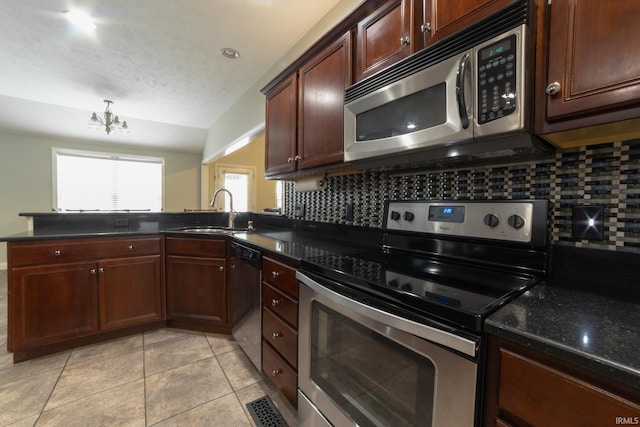 kitchen featuring sink, an inviting chandelier, kitchen peninsula, stainless steel appliances, and decorative backsplash