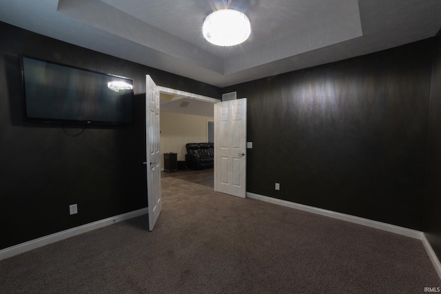 carpeted empty room with a raised ceiling