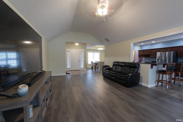 living room with lofted ceiling, ceiling fan with notable chandelier, and dark wood-type flooring