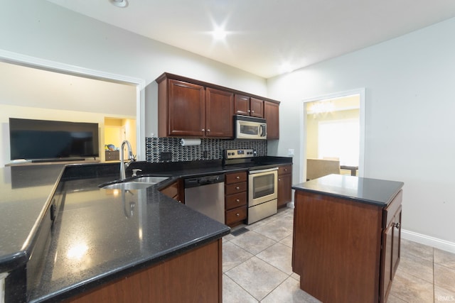 kitchen with sink, light tile patterned floors, appliances with stainless steel finishes, backsplash, and a kitchen island