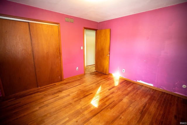 unfurnished bedroom with a closet and hardwood / wood-style floors