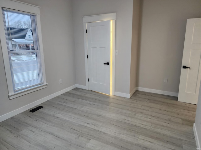 empty room with a healthy amount of sunlight and light hardwood / wood-style flooring