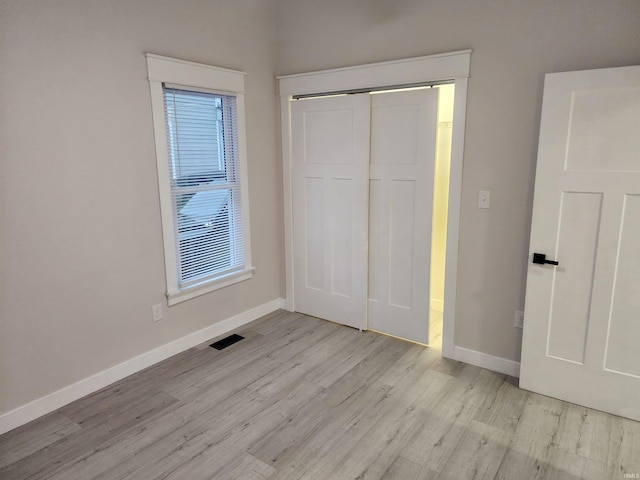 unfurnished bedroom with a closet, multiple windows, and light hardwood / wood-style flooring