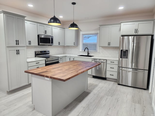 kitchen featuring wooden counters, a kitchen island, sink, hanging light fixtures, and appliances with stainless steel finishes