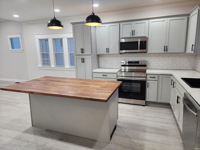 kitchen featuring hanging light fixtures, wooden counters, gray cabinetry, and stainless steel appliances