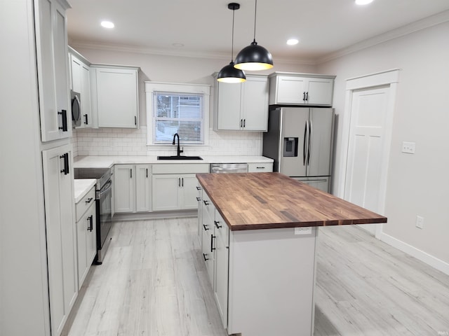 kitchen featuring wood counters, stainless steel appliances, decorative light fixtures, a kitchen island, and sink