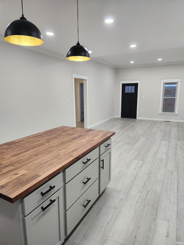 kitchen with butcher block counters, light hardwood / wood-style flooring, and decorative light fixtures