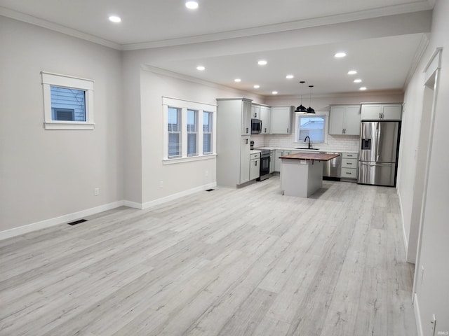 kitchen with wooden counters, a kitchen island, pendant lighting, appliances with stainless steel finishes, and gray cabinetry