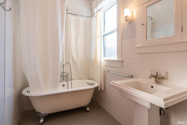 bathroom featuring a wealth of natural light, tile walls, shower / tub combo, and sink