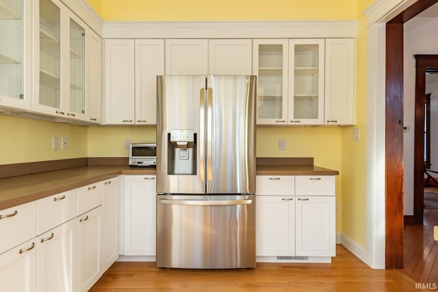 kitchen featuring light wood-type flooring, stainless steel fridge with ice dispenser, and white cabinetry