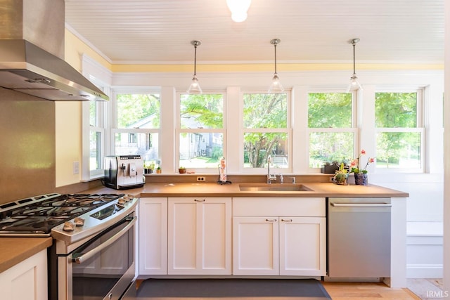 kitchen featuring hanging light fixtures, white cabinets, appliances with stainless steel finishes, and range hood