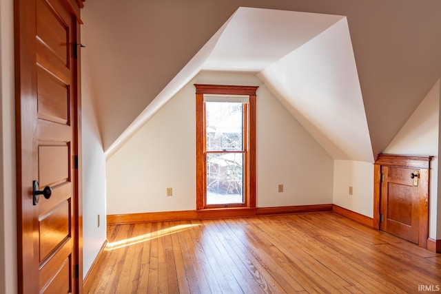 additional living space featuring vaulted ceiling and light hardwood / wood-style flooring