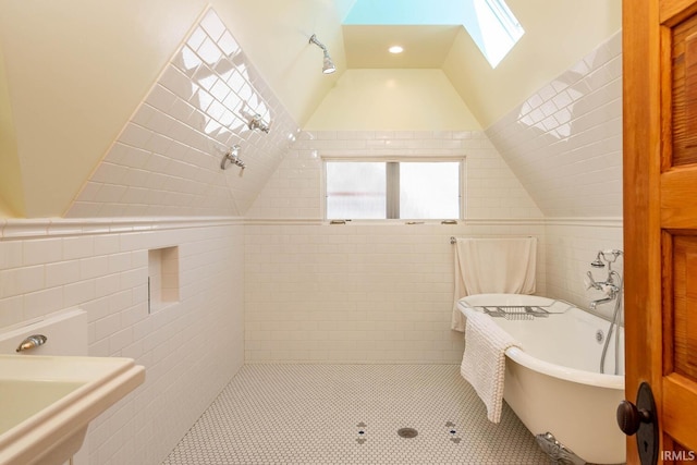 bathroom with a tub, tile walls, vaulted ceiling with skylight, and a wealth of natural light