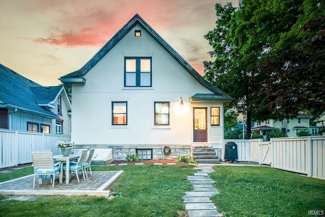 back house at dusk with a yard and a patio