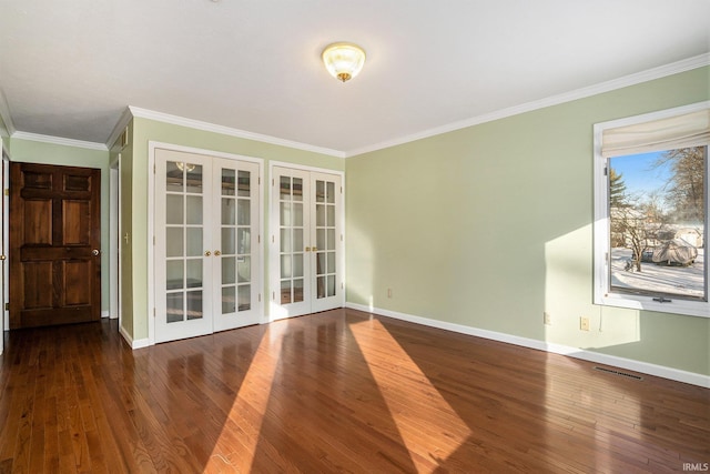 empty room with dark hardwood / wood-style floors, ornamental molding, and french doors