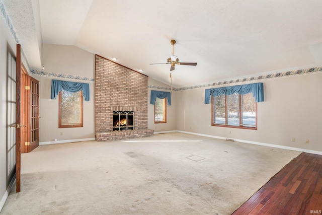 unfurnished living room with ceiling fan, carpet flooring, lofted ceiling, and a fireplace