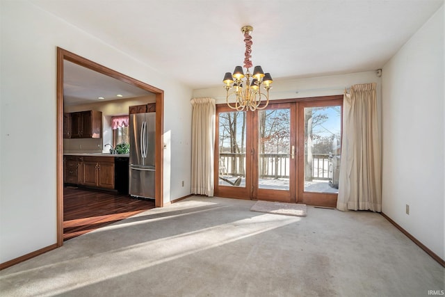 unfurnished room with carpet, french doors, and an inviting chandelier