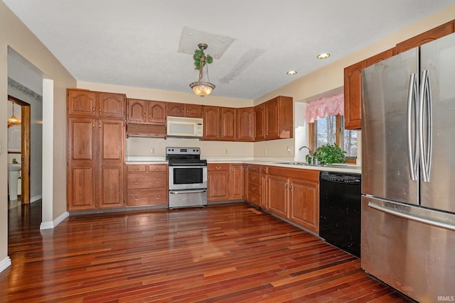 kitchen with dark wood-type flooring, sink, pendant lighting, and stainless steel appliances