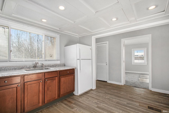 kitchen featuring white refrigerator, a healthy amount of sunlight, coffered ceiling, and sink