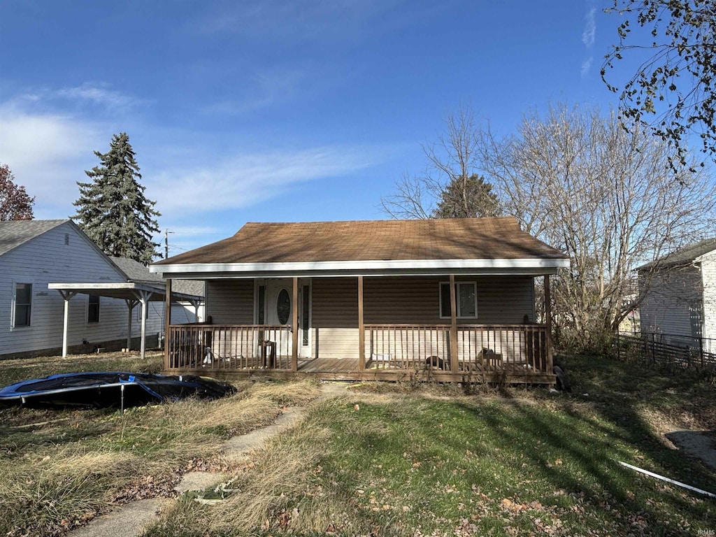 back of house featuring a trampoline and a yard