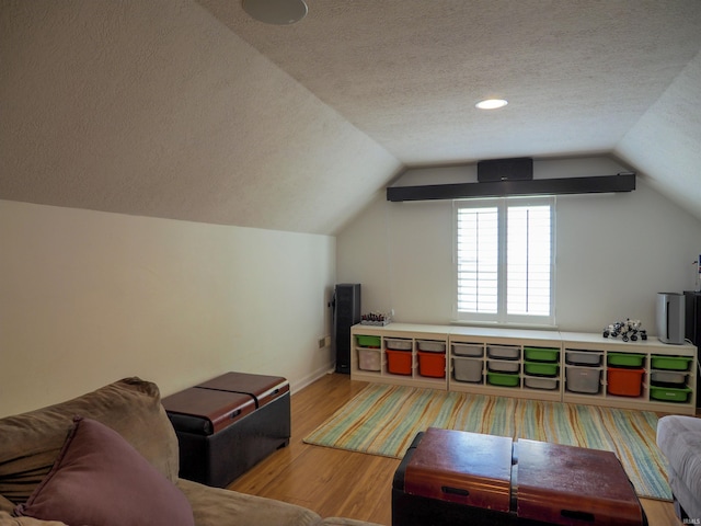 additional living space featuring hardwood / wood-style flooring, a textured ceiling, and vaulted ceiling