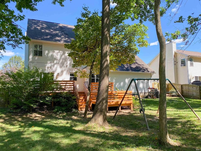 rear view of house featuring a wooden deck, a playground, and a yard