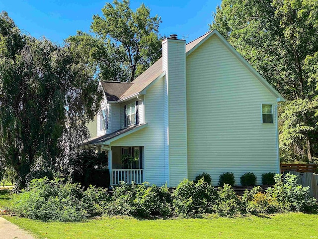 view of home's exterior with covered porch and a lawn