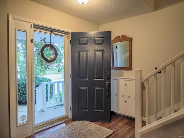 entrance foyer with dark wood-type flooring and a textured ceiling