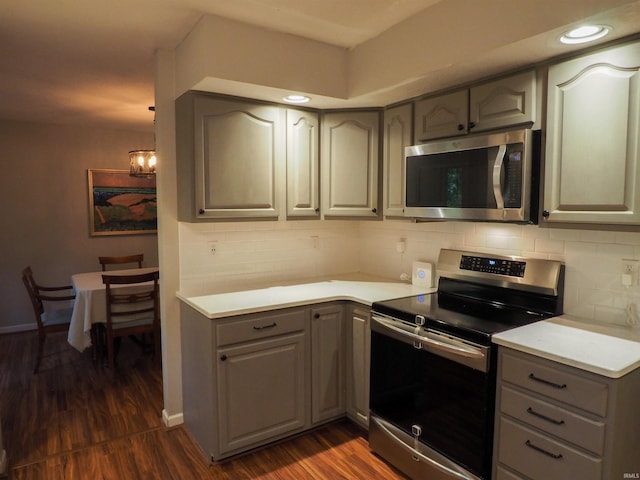 kitchen featuring appliances with stainless steel finishes, dark hardwood / wood-style flooring, tasteful backsplash, and a notable chandelier