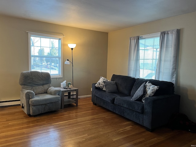 living room with a baseboard heating unit and dark hardwood / wood-style floors