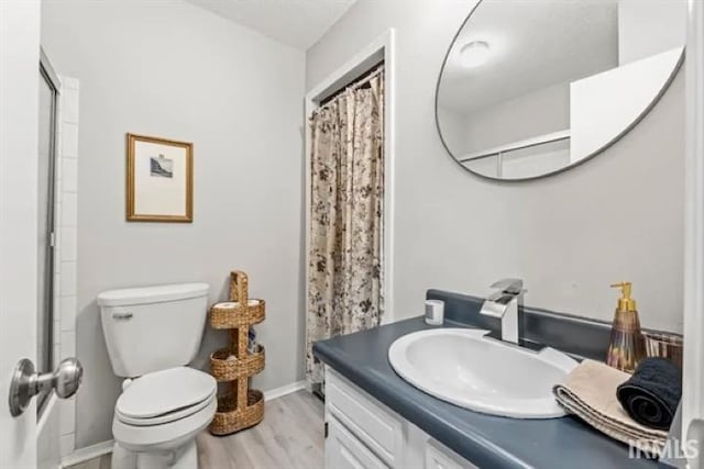 bathroom with hardwood / wood-style flooring, toilet, vanity, and a shower with curtain