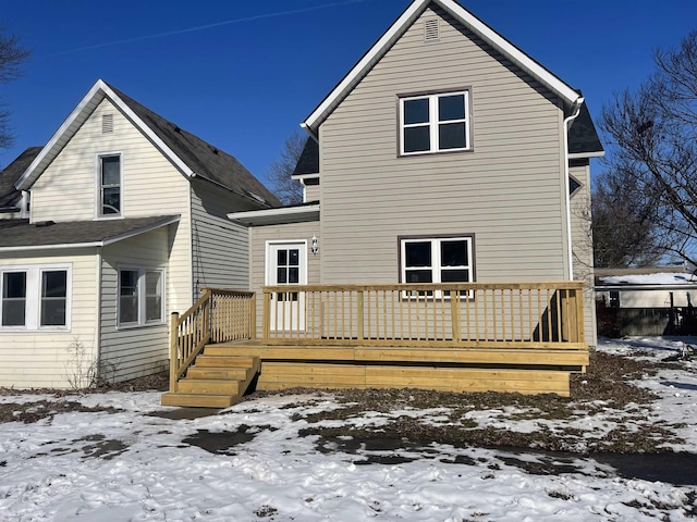 snow covered rear of property with a deck