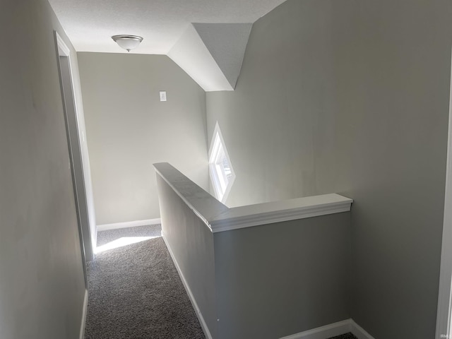 corridor with a textured ceiling, lofted ceiling, and carpet flooring