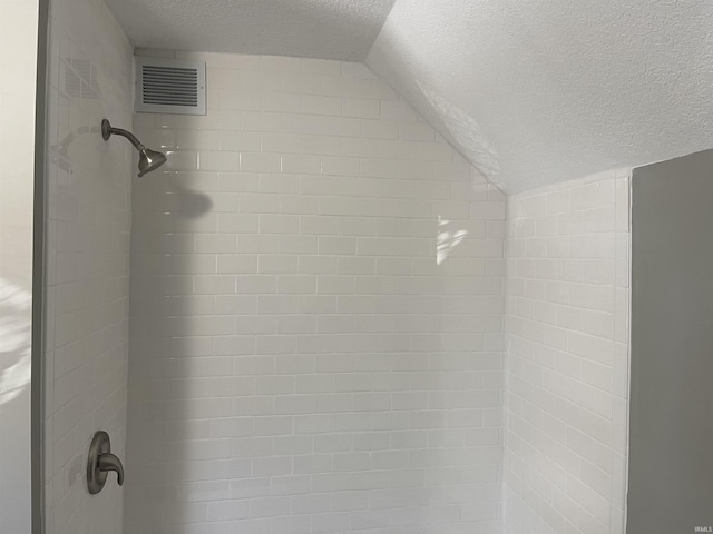 room details featuring a textured ceiling and a tile shower