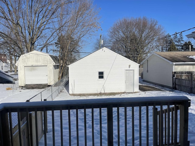 yard covered in snow featuring a garage and an outbuilding