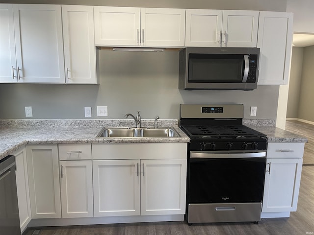 kitchen with dark wood-type flooring, sink, stainless steel appliances, and white cabinetry