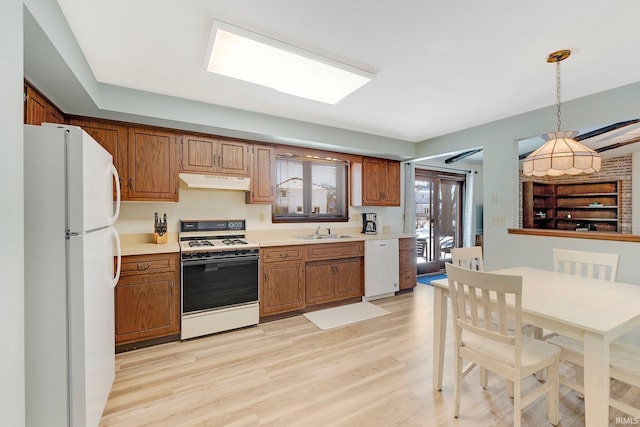 kitchen featuring decorative light fixtures, sink, white appliances, and light hardwood / wood-style flooring