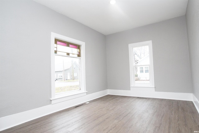 unfurnished room with a healthy amount of sunlight and hardwood / wood-style floors