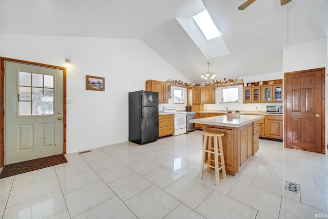 kitchen with a kitchen island, white range with electric cooktop, black fridge, a breakfast bar, and lofted ceiling with skylight