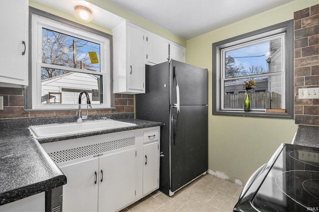 kitchen with white cabinets, black refrigerator, sink, backsplash, and electric stove