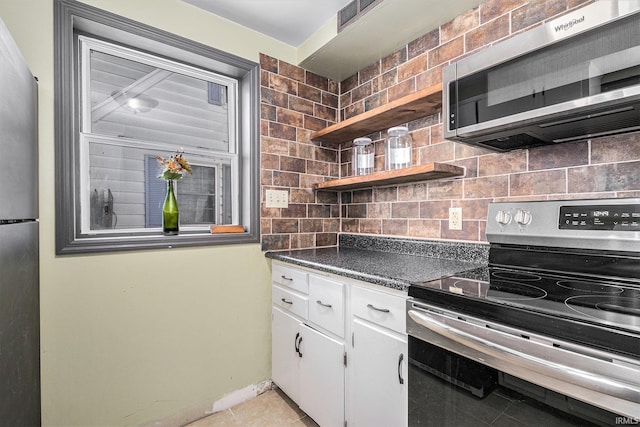 kitchen featuring backsplash, white cabinetry, appliances with stainless steel finishes, and light tile patterned flooring