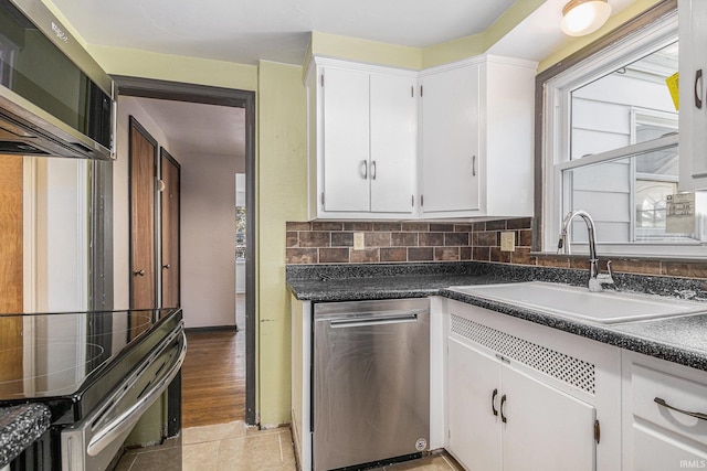 kitchen featuring white cabinets, stainless steel appliances, decorative backsplash, sink, and light tile patterned flooring