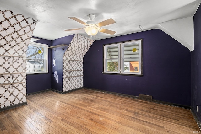 additional living space with ceiling fan, a wealth of natural light, wood-type flooring, and lofted ceiling