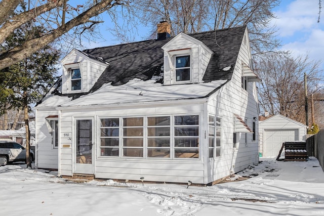 view of front of house with a garage and an outbuilding