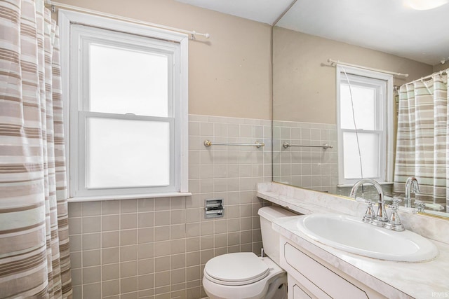 bathroom with toilet, vanity, and tile walls